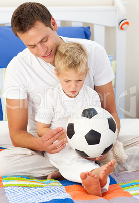 Blond little boy and his father playing with a soccer ball