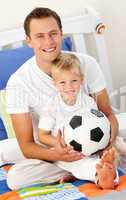 Close-up of a little boy and his father playing with a soccer ba