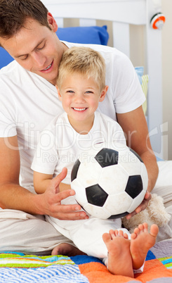 Smiling little boy and his father playing with a soccer ball