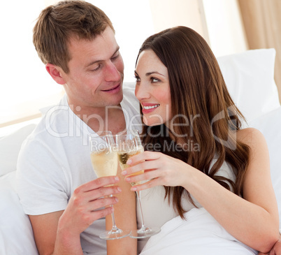 Romantic couple drinking champagne lying in bed