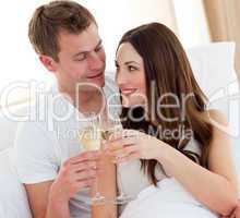 Romantic couple drinking champagne lying in bed