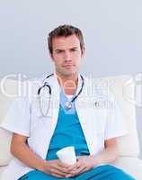Serious male doctor drinking coffee