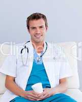 Smiling male doctor drinking coffee