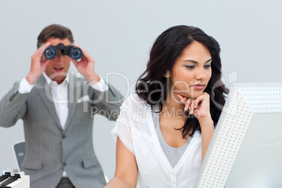 Mature businessman looking his colleague's computer through bino