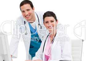 Two smiling doctors working at a computer