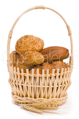 Fresh buns and ears of wheat in a basket on a white background