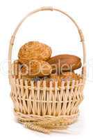 Fresh buns and ears of wheat in a basket on a white background