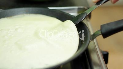 Preparation of pancakes on frying pan.