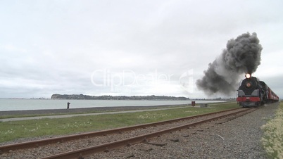 steam train  and carriages speed past beach