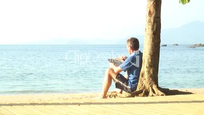 Mann liest ein Buch am Strand