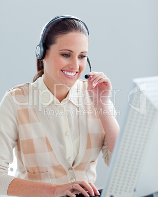 Smiling businesswoman working at a computer with headset on