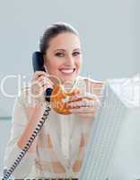 Positive businesswoman on phone eating a donnut