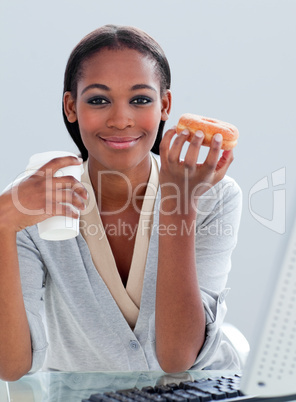 Portrait of an ethnic businesswoman drinking coffee and eating d