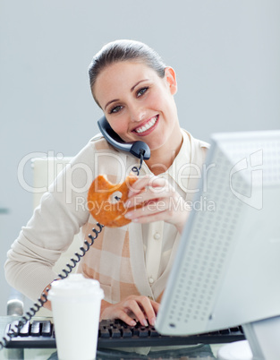 Self-assured businesswoman on phone eating a donnut