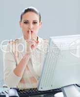 Attractive businesswoman at a computer asking for silence