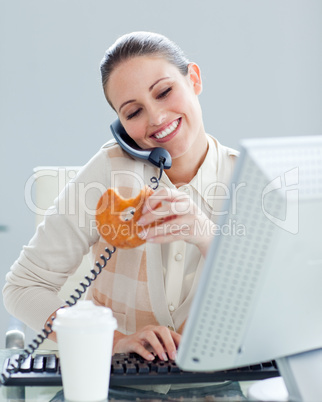 Confident businesswoman on phone eating a donnut