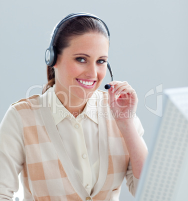 Charming businesswoman working at a computer with headset on