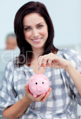 Charismatic businesswoman saving money in a piggy-bank
