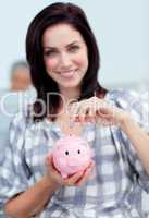 Charismatic businesswoman saving money in a piggy-bank