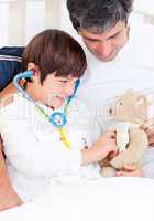 Caring father and his sick son playing with a stethoscope