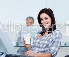 Radiant businesswoman holding a drinking cup at her desk