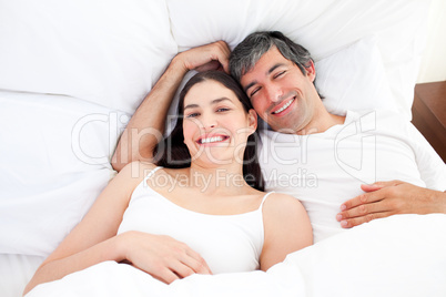 Smiling couple hugging lying in their bed