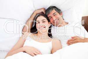 Smiling couple hugging lying in their bed