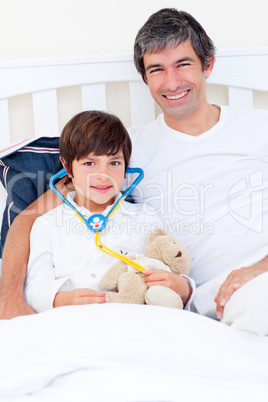 Smiling father and his sick son playing with a stethoscope