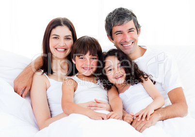 Portrait of a happy family sitting on a bed