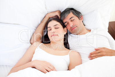 Affectionate couple hugging lying in their bed