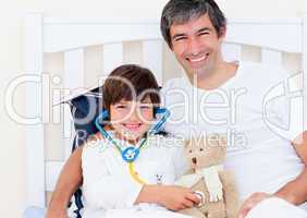 Cheerful father and his sick son playing with a stethoscope