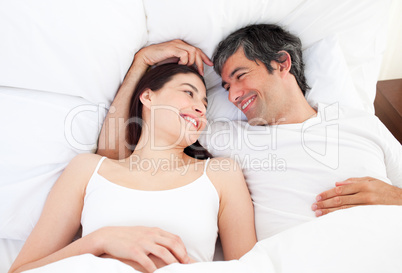 Enamored couple hugging lying in their bed