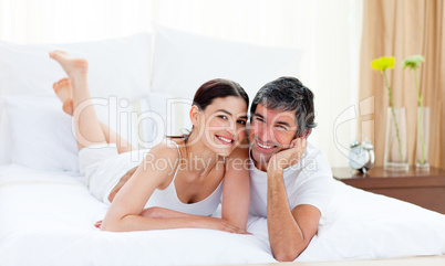 Loving couple cuddling lying on their bed