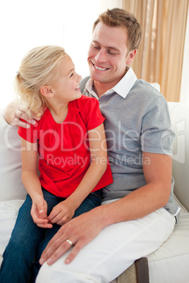 Adorable little girl sitting on sofa with her father