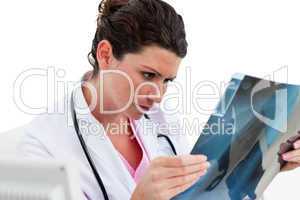 Serious female doctor looking at X-ray in his office