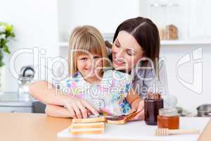 Smiling little girl and her mother preparing toasts