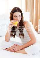 Relaxed woman drinking orange juice on bed
