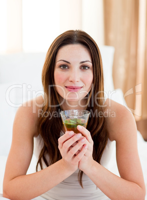 Young brunette woman drinking tea sitting on bed