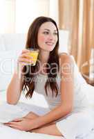 Beautiful woman drinking orange juice on bed