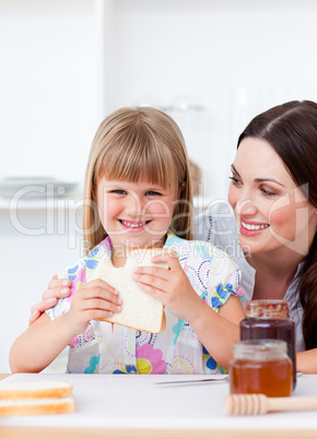 Happy little girl and her mother eating slices of bread