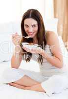 Attractive woman eating cereals sitting on bed