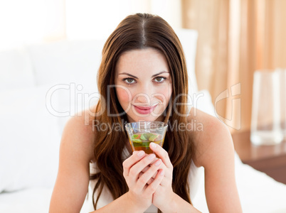 Portrait of a young woman drinking tea sitting on bed