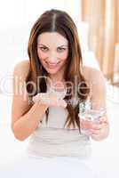 Brunette woman taking a pill sitting on bed