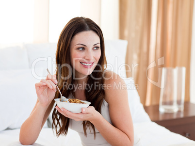 Pretty woman eating cereals sitting on bed