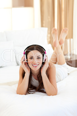 Pretty woman listening music lying on bed