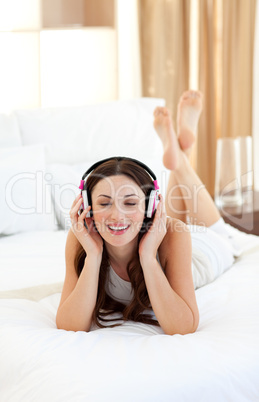 Brunette woman listening music lying on bed