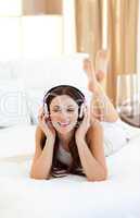 Brunette woman listening music lying on bed