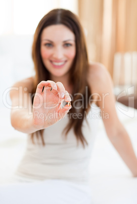 Attractive woman taking a pill sitting on bed