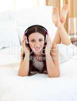 Charming woman listening music lying on bed
