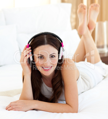 Smiling woman listening music lying on bed